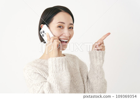 中年婦女在撥打智慧型手機時指向右側，白色背景 109369354