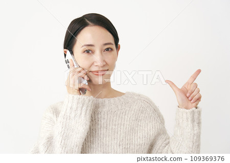 Middle-aged woman signing a check while calling on a smartphone, white background Middle-aged woman signing a check while calling on a smartphone, white background 109369376