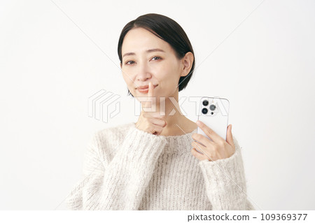 A middle-aged woman holding a smartphone and posing in a secret pose, white background A middle-aged woman holding a smartphone and posing in a secret pose, white background 109369377