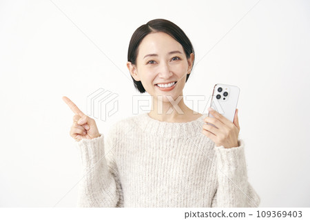 Middle-aged woman holding a smartphone and pointing to the left, white background Middle-aged woman holding a smartphone and pointing to the left, white background 109369403