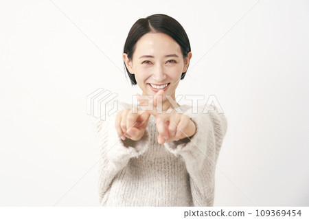 Middle-aged woman making a cross-mark gesture with her finger, white background 109369454