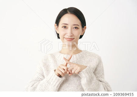 Middle-aged woman making a cross-mark gesture with her finger, white background Middle-aged woman making a cross-mark gesture with her finger, white background 109369455