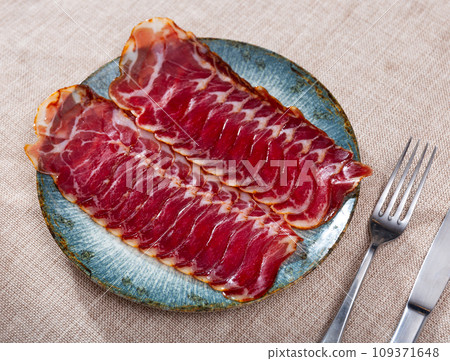 Sliced Spanish dry cured pork neck on plate. Traditional meat delicacies Sliced Spanish dry cured pork neck on plate. Traditional meat delicacies 109371648