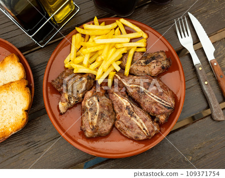Dish with delicious appetizing baked pork cheeks with french fries for dinner close up Dish with delicious appetizing baked pork cheeks with french fries for dinner close up 109371754