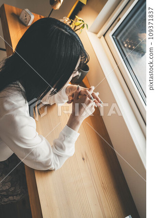 Hand of a woman sitting at a table by the window 109371837