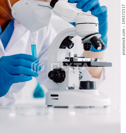 biochemical research scientist team working with microscope for coronavirus vaccine development in pharmaceutical research labolatory, selective focus 109372517