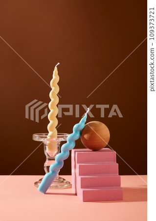 Two twisted candles are displayed with some props on the table. Brown background. Exquisite space for product display, magazine posting or other purposes. 109373721