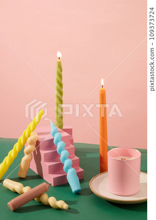 Twisted candles of different colors are placed around the pink terraced podium, next to a jar of scented candles placed on a ceramic plate. Space for birthdays. 109373724