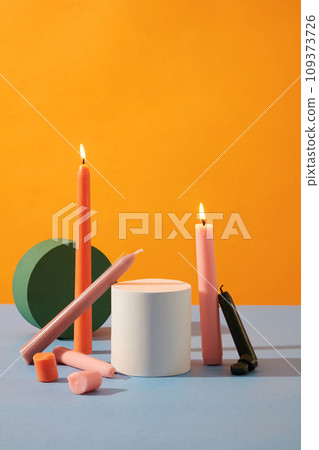 Front view of colored candles and round wooden platforms are displayed together on a yellow-purple background. Space for product display and advertising. Front view of colored candles and round wooden platforms are displayed together on a yellow-purple background. Space for product display and advertising. 109373726