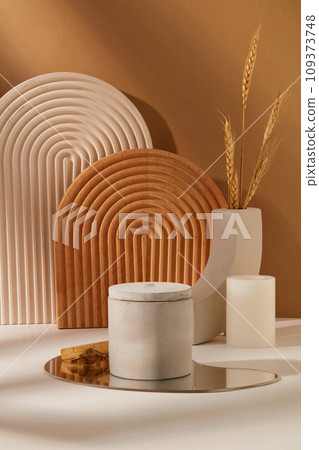 A jar of scented candles is placed on an acrylic sheet. Arched platforms and props decorated the tables. Brown and white background. Copy space for scented candle ads. A jar of scented candles is placed on an acrylic sheet. Arched platforms and props decorated the tables. Brown and white background. Copy space for scented candle ads. 109373748