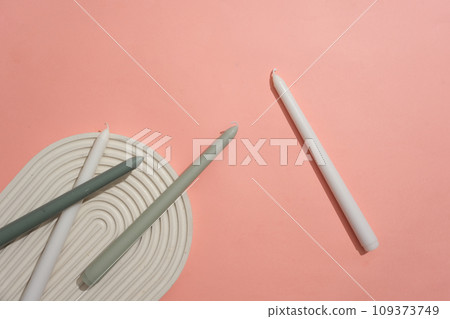 White and gray candles are displayed on a pink background with a domed podium. Empty space for product display. Creative space for advertising and more. White and gray candles are displayed on a pink background with a domed podium. Empty space for product display. Creative space for advertising and more. 109373749