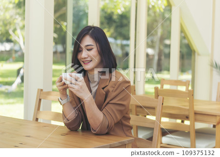 Asian Woman drink black coffee hand holding cup at green garden cafe. Young woman smile face love drink coffee. Beauty woman drinking black coffee in coffee shop holding freshness cup. Coffee lover 109375132