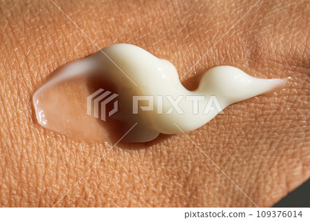 A smear of white moisturizer or sunscreen on a woman's hand. A smear of white moisturizer or sunscreen on a woman's hand. 109376014