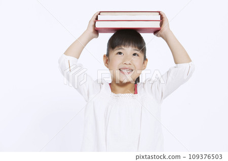 A girl with a book on her head 109376503