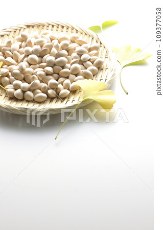 Ginkgo seeds and leaves in a basket are photographed against a white background 109377058