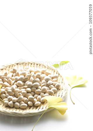 Ginkgo seeds and leaves in a basket are photographed against a white background 109377059