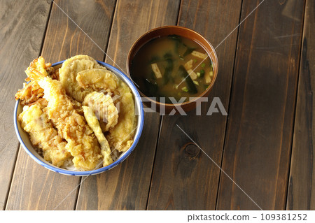 A tempura bowl with lots of ingredients such as shrimp, chikuwa, green beans, pumpkin, sweet potato, and lotus root, and miso soup. 109381252