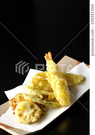 Assorted tempura of shrimp, chikuwa, green beans, pumpkin, sweet potato, and lotus root photographed against a black background Assorted tempura of shrimp, chikuwa, green beans, pumpkin, sweet potato, and lotus root photographed against a black background 109381569