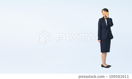 Cropped full-body photo of a woman wearing a suit talking on a smartphone Cropped full-body photo of a woman wearing a suit talking on a smartphone 109381611