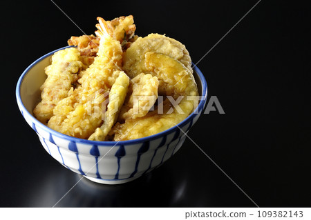 A photo of a tempura bowl with lots of ingredients such as shrimp, chikuwa, green beans, pumpkin, sweet potato, and lotus root against a black background A photo of a tempura bowl with lots of ingredients such as shrimp, chikuwa, green beans, pumpkin, sweet potato, and lotus root against a black background 109382143