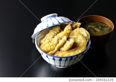 A tempura bowl with lots of ingredients such as shrimp, chikuwa, green beans, pumpkin, sweet potato, and lotus root, and miso soup. 109382229