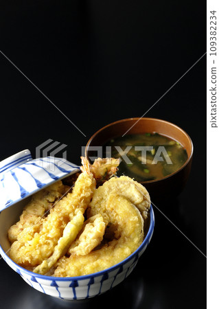 A tempura bowl with lots of ingredients such as shrimp, chikuwa, green beans, pumpkin, sweet potato, and lotus root, and miso soup. 109382234