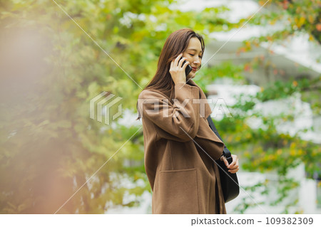 A woman in a coat walking outdoors 109382309