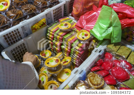 Many varieties of traditional snacks sold in the Marketplace in dawn time in Surabaya, East Java, Indonesia. Many varieties of traditional snacks sold in the Marketplace in dawn time in Surabaya, East Java, Indonesia. 109384372
