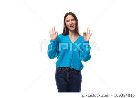 young charming brunette lady dressed in a blue V-neck sweater actively jests on a white background 109384816