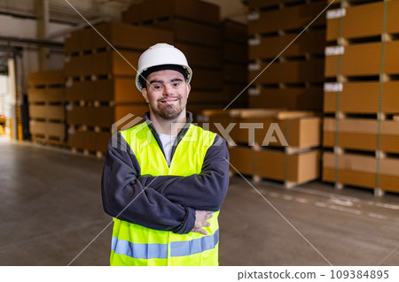 Portrait of young man with Down syndrome working in factory, warehouse. Concept of workers with disabilities, support in workplace. 109384895