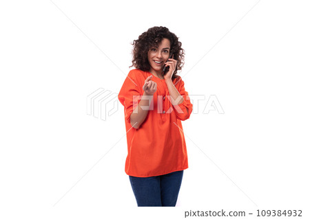 young caucasian business woman with a curly hairstyle dressed in an orange shirt speaks on the phone 109384932