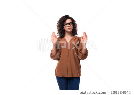 young well-groomed caucasian woman with curly black hair stands thoughtfully on a white background 109384943