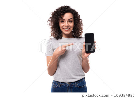 young funny pretty brunette curly caucasian lady in casual jeans and a t-shirt demonstrates a 109384985