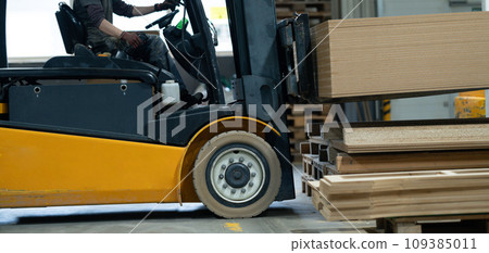 Close up of forklift working in warehouse. Industrial lift truck, jitney lifting and moving materials in factory. Warehouse banner with copy space. Close up of forklift working in warehouse. Industrial lift truck, jitney lifting and moving materials in factory. Warehouse banner with copy space. 109385011