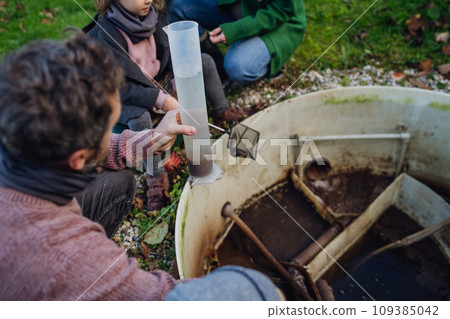 The family checks the water quality in the home wastewater treatment system. Concept of sustainable family living. 109385042
