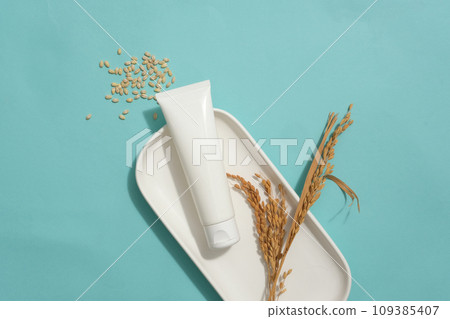 Cosmetic tube without label decorated with wheat ears on a dish. A handful of wheat seeds featured. Empty label tube for natural beauty product advertising Cosmetic tube without label decorated with wheat ears on a dish. A handful of wheat seeds featured. Empty label tube for natural beauty product advertising 109385407
