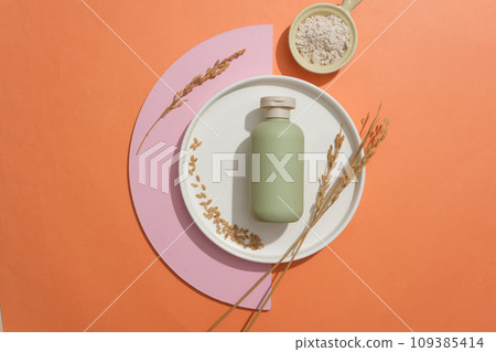 Ceramic dish in round shaped with unbranded bottle placed on with wheat ears. A bowl of rice bran featured. Branding mockup design with blank label Ceramic dish in round shaped with unbranded bottle placed on with wheat ears. A bowl of rice bran featured. Branding mockup design with blank label 109385414