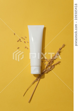 Top view of a unlabeled tube in white color decorated over yellow background with wheat seeds. Natural cosmetic concept. Empty label for branding mockup Top view of a unlabeled tube in white color decorated over yellow background with wheat seeds. Natural cosmetic concept. Empty label for branding mockup 109385418