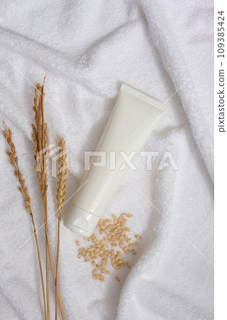 White towel decorated as a background with wheat ears, wheat seeds and unbranded tube displayed on. Natural skin care concept with empty label White towel decorated as a background with wheat ears, wheat seeds and unbranded tube displayed on. Natural skin care concept with empty label 109385424