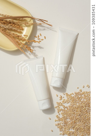 Two blank label white tubes are displayed with a heap of rice wheat and yellow dish featured wheat ears. Rice water can help improve many eye problems Two blank label white tubes are displayed with a heap of rice wheat and yellow dish featured wheat ears. Rice water can help improve many eye problems 109385431