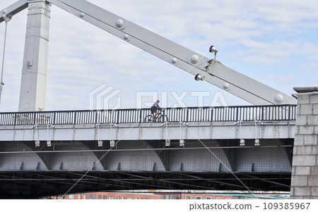 Man riding on bicycle across the bridge in the city. Man riding on bicycle across the bridge in the city. 109385967