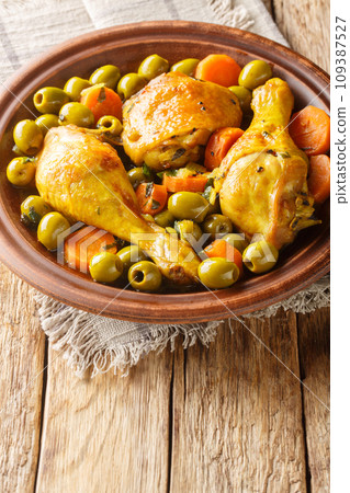 Tajine Zitoune is an Algerian stew dish that consists of chicken cooked with carrots and green olives using north African spices close-up. Vertical Tajine Zitoune is an Algerian stew dish that consists of chicken cooked with carrots and green olives using north African spices close-up. Vertical 109387527