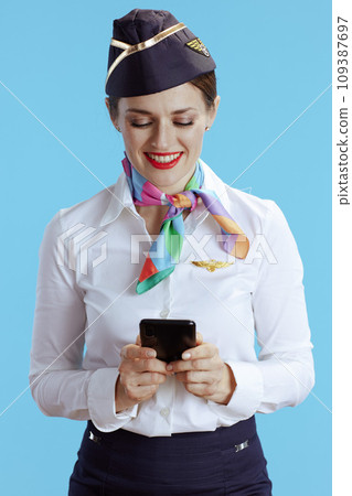 smiling elegant female flight attendant on blue using phone smiling elegant female flight attendant on blue using phone 109387697