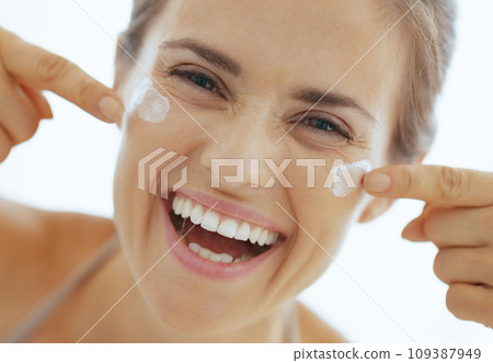 Happy young woman having fun time while applying cream in bathro Happy young woman having fun time while applying cream in bathro 109387949