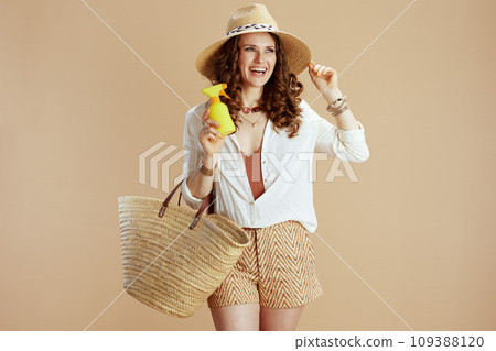 happy trendy woman in white blouse and shorts isolated on beige 109388120