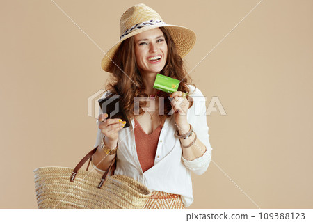 happy trendy female in blouse and shorts using phone on beige 109388123