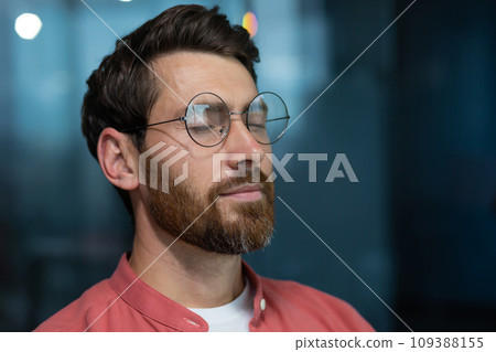 Close up of mature thinking businessman meditating and thinking with closed eyes at workplace inside office, man in red shirt resting and breathing. 109388155