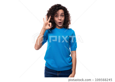 young curly woman in a blue sweater shows a gesture of ok 109388245