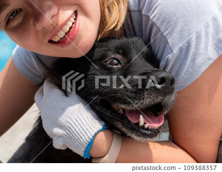 Young girl hugging and petting caged stray dog in pet shelter. People, Animals, Volunteering And Helping Concept. 109388357