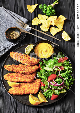 breaded fish fillet with salad on black plate breaded fish fillet with salad on black plate 109388637